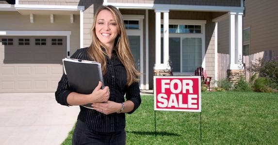 woman-agent-realtor-standing-outside-home-for-sale_573x300